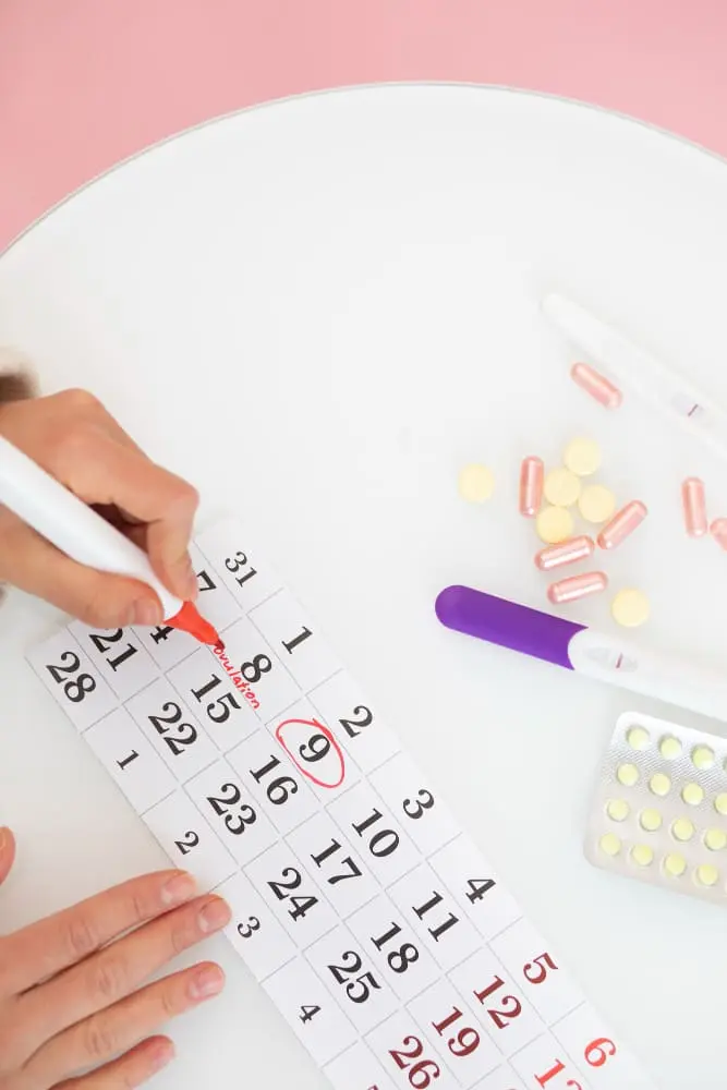 ovulation-test-close-up-hand-marking-calendar-high-angle